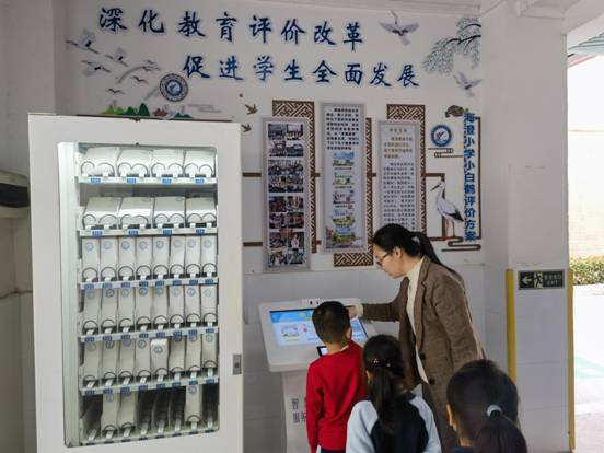 图3 何三兰老师指导学生兑换小白鹤评价积分和领取积分奖品。拍摄时间为2022年12月1日，拍摄者：万赐龙，地点：珠海市三灶镇海澄小学