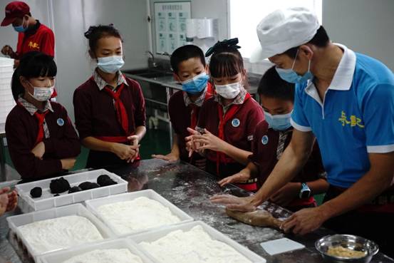 许叶阳在非遗进校园活动中教授学生用传统饼具制作月饼。摄影：林倩明
